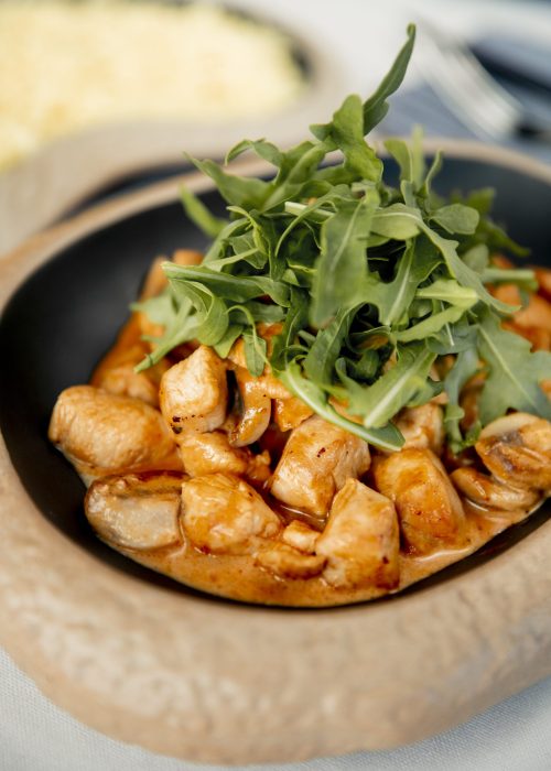chopped chicken breast in sauce and arugula